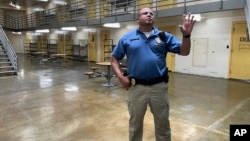 Maj. Albin Narvaez waves to a correctional officer in a secure observation room as he stands in the common area of a prisoner housing unit at the Fulton Reception and Diagnostic Center, July 13, 2023, in Fulton, Missouri.