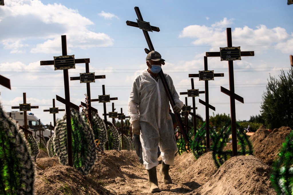 Photo: A volunteer places a cross with a number to a grave of one of unidentified people killed by Russian troops, as Russia's attack on Ukraine continues, during a mass burial ceremony in the town of Bucha, in Kyiv region, Ukraine September 2, 2022. Credit: REUTERS/Vladyslav Musiienko
