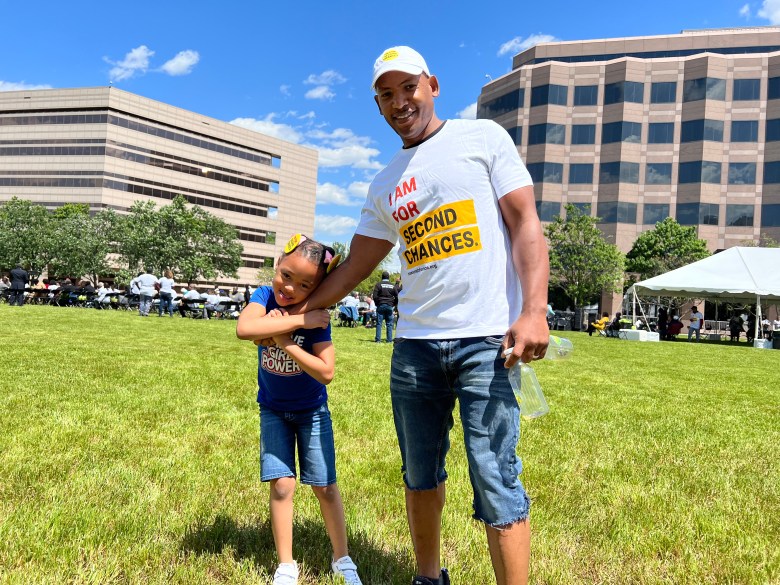 Corey Purdie stands with his daughter, who grabs her father's hand. 