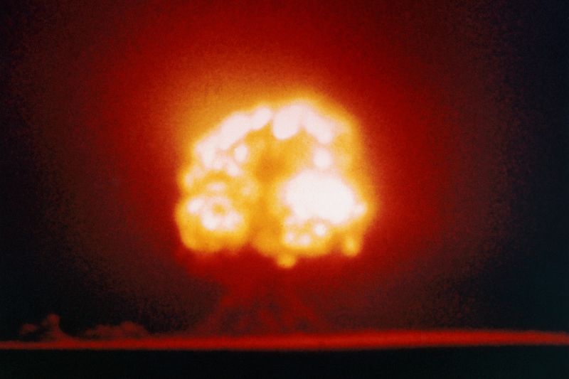 A giant orange mushroom cloud explodes on the horizon during the first atomic bomb test in New Mexico on July 16, 1945.