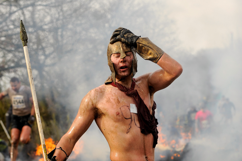 A competitor dressed as a Spartan warrior takes part in the 2010 Tough Guy race in England, as fire rages in the background.