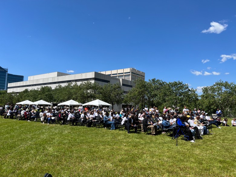 People sit in chair on the grass beside a large building.