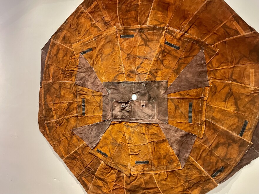 Artist Russell Craig stitched together scorched, fire retardant clothes in a piece that represents his journey through the prison system. The pale dot painted in the center represents a “light at the end of the tunnel.”