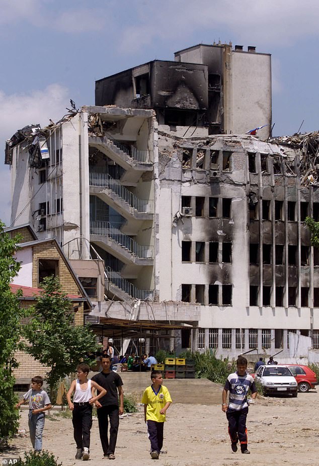 A group of children walk in front of a damaged PTT building following NATO air-strikes in Pristina, Kosovo on 9 June 1999