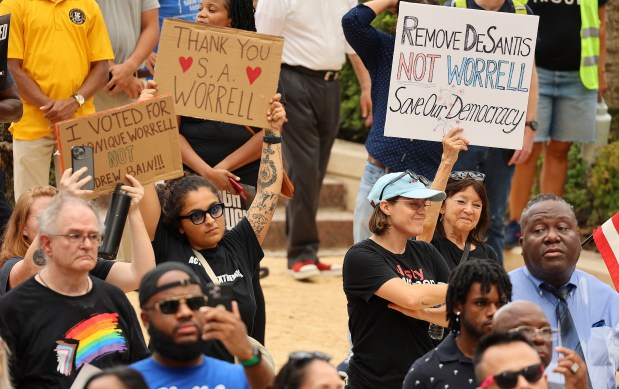 Demonstrators hold signs during a Rally for Democracy at Orlando City Hall, Thursday, Aug. 10, 2023 in Orlando, Fla. The rally was in response to Ninth Judicial Circuit State Attorney Monique Worrell's suspension by Gov. Ron DeSantis. (Stephen M. Dowell/Orlando Sentinel)