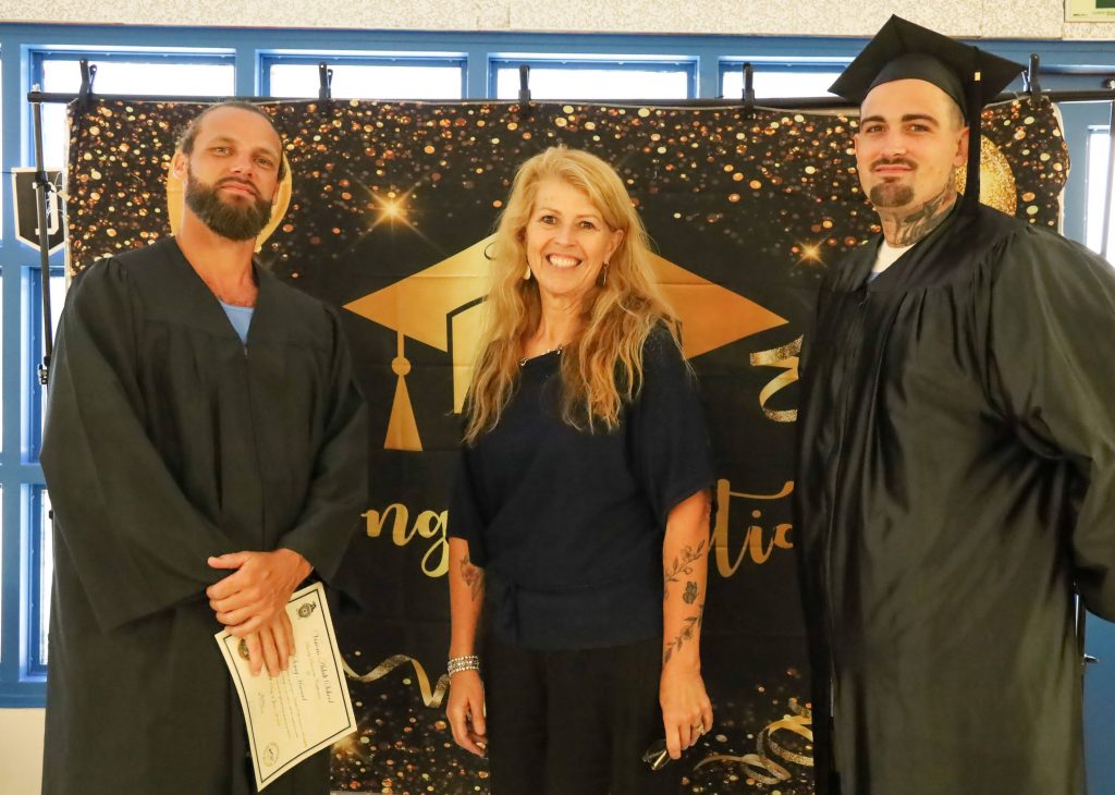 Graduates pose for photos with prison staff during the ceremony at COR.