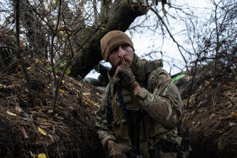 Slavian, a former Russian special forces sergeant who now fights for Ukraine after living in the country for a decade with his Ukrainian wife, gestures to keep quiet as he moves along front-line tenches toward a Russian position in Zaporizhzhia, Ukraine, on Oct. 27, 2022.