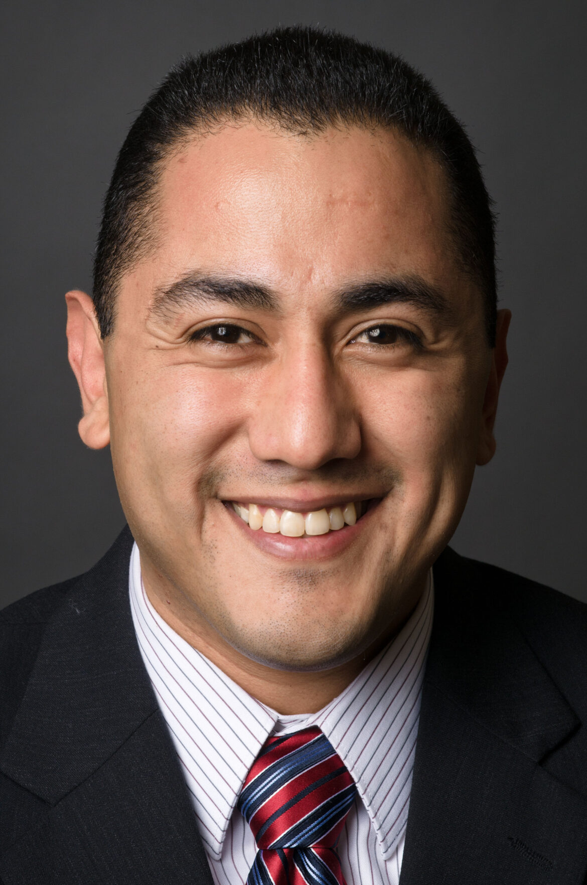 California juvenile justice: A person with short dark hair wearing a dark suit and a tie smiling into the camera