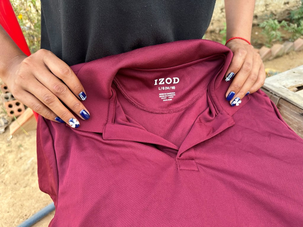 A former inmate at Correctional Center 2 holds a polo shirt with an IZOD label that she said was made on prison grounds.