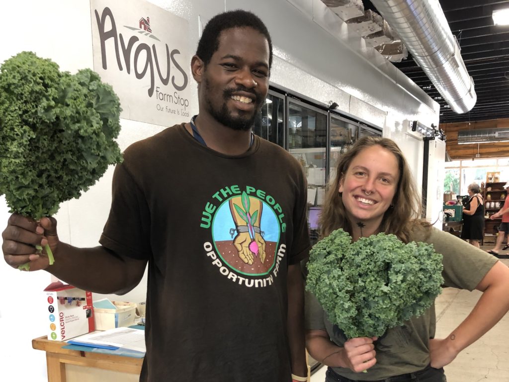 We the People Opportunity Farm intern Donte Smith, left, delivers fresh organic kale August 3, 2023, to Argus Farm Stop in Ann Arbor, Michigan. Sale of organic vegetables helps the nonprofit support formerly incarcerated citizens as they return home from prison. Photo courtesy of We the People Opportunity Farm