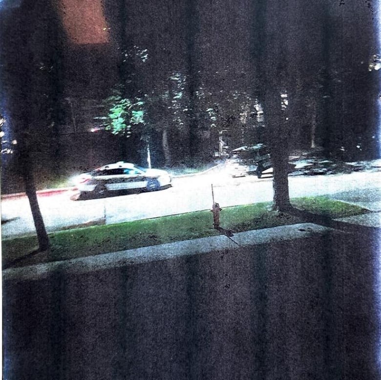 The photo is taken at night. You can see a black and while Winnipeg police cruiser car parked on the street. There is also a police SVU parked in a neighbours driveway.