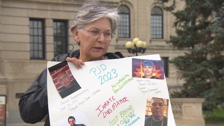 A woman with eyeglasses holding a paper banner with photos stuck on it. 