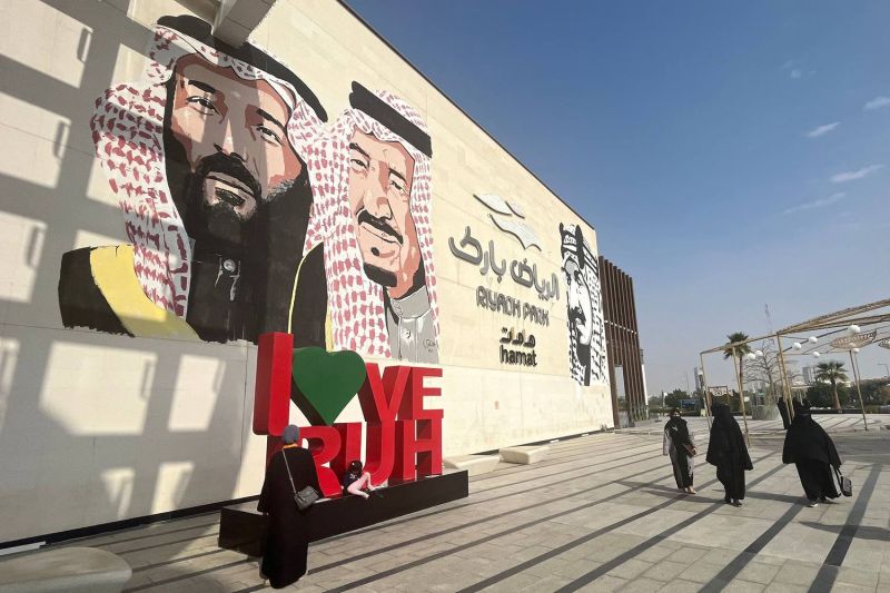 Saudi women walk past a mural depicting Saudi King Salman (center), Crown Prince Mohammed bin Salman (left), and late King Abdulaziz bin Abdul Rahman (right), the founder of the modern Kingdom of Saudi Arabia, at a park in the capital, Riyadh, on Jan. 16.