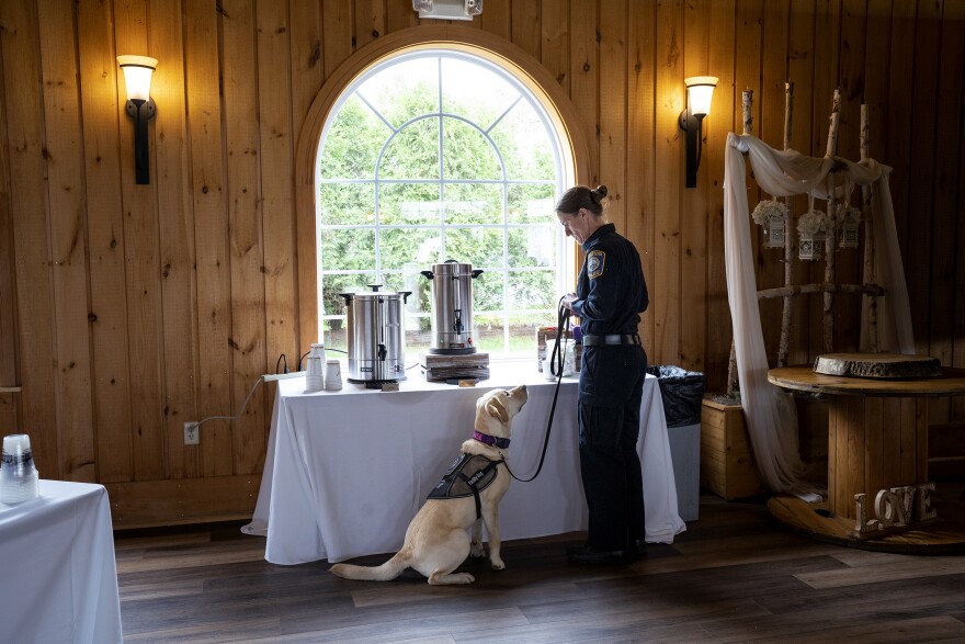 Groton Officer Heather McClelland makes herself coffee while K-9 Chase looks on, hopefully. They are at the Crisis Intervention Training Awards, hosted by the Connecticut Alliance to Benefit Law Enforcement (CABLE), where they will be receiving an award for their service responding to the attack on Bristol police officers last October.