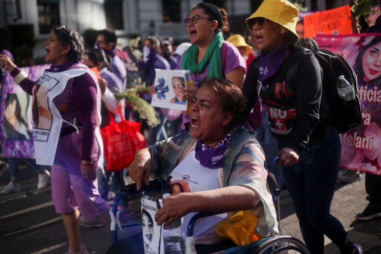 Demonstrators carry photos of missing girls and women during a march in Mexico City against gender-based violence. Many are also wearing green and purple, symbols of the movement.