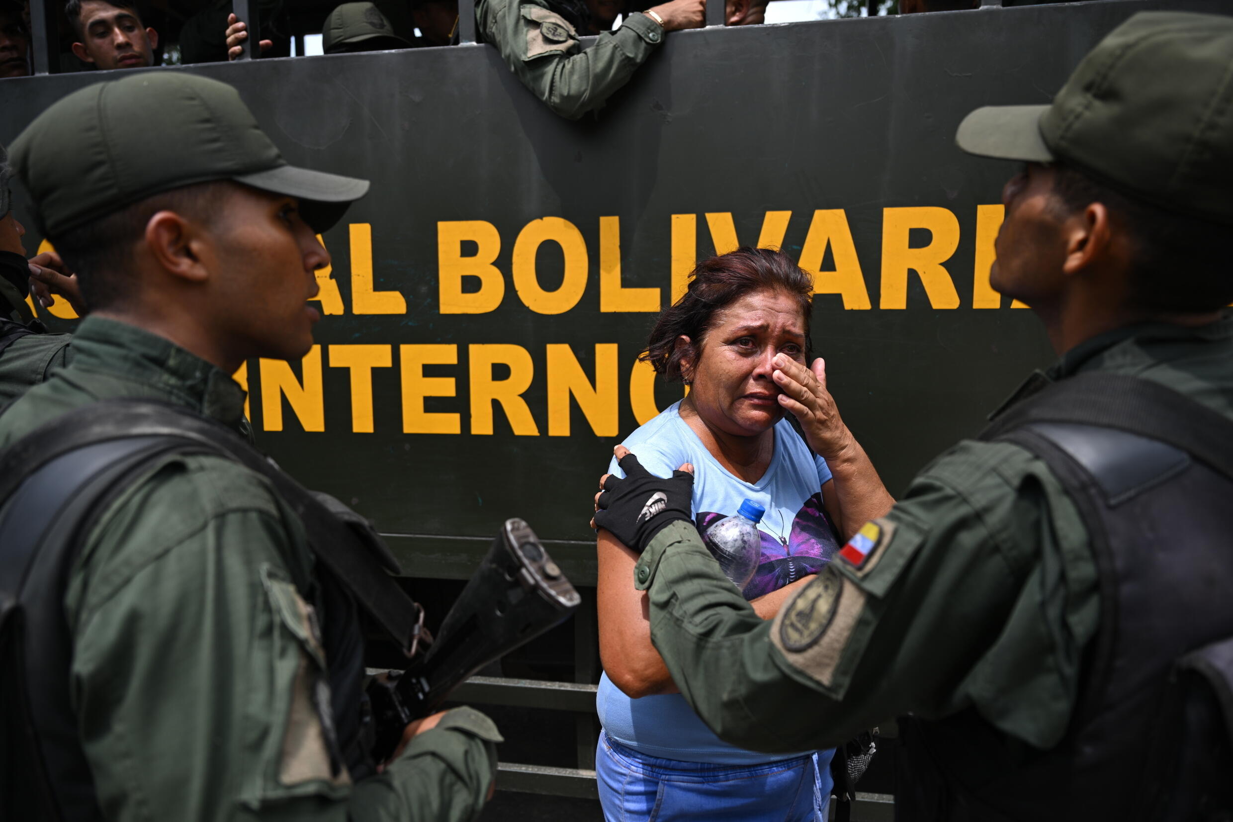 A relative of an inmate is comforted by Venezuela national guard members after authorities stormed the gang-run prison