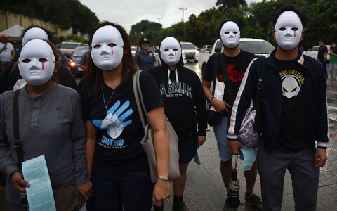 Protesters wearing masks depicting victims of extra judicial killings