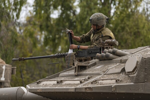 An Israeli soldier works on a tank at a staging ground near the Israeli Gaza border, southern Israel, Monday, Oct. 9, 2023. The militant Hamas rulers of the Gaza Strip carried out an unprecedented, multi-front attack on Israel at daybreak Saturday, firing thousands of rockets as dozens of Hamas fighters infiltrated the heavily fortified border in several locations, killing hundreds and taking captives. Palestinian health officials reported scores of deaths from Israeli airstrikes in Gaza. (AP Photo/Tsafrir Abayov)