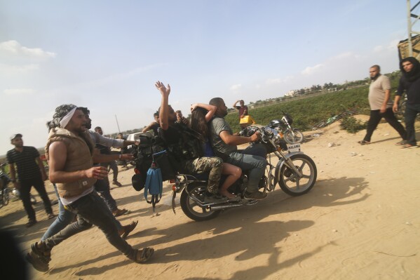 FILE - Palestinians transport a captured Israeli civilian, center, from Kfar Azza kibbutz into the Gaza Strip on Saturday, Oct. 7, 2023. The militant Hamas rulers of the Gaza Strip carried out an unprecedented, multi-front attack on Israel at daybreak Saturday, firing thousands of rockets as dozens of Hamas fighters infiltrated the heavily fortified border in several locations by air, land, and sea and catching the country off-guard on a major holiday. (AP Photo/Hatem Ali, File)