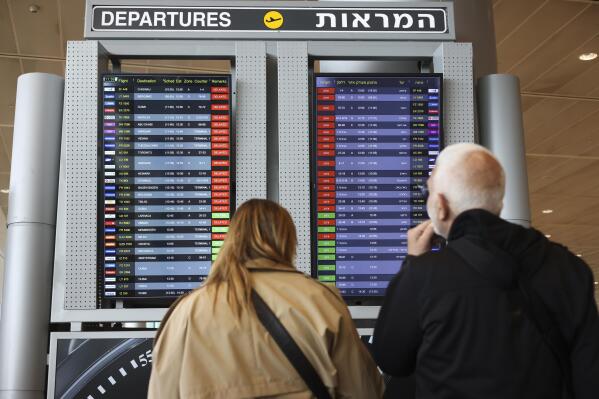 Passengers look at the monitor displaying delayed flights at Ben Gurion airport, near Tel Aviv, Israel, Monday, March 27, 2023. Israeli Airports Authority says flights out of main international airport have been grounded following strike cal. Israel's largest trade union group launched a strike across a broad swath of sectors, joining a surging protest movement against Prime Minister Benjamin Netanyahu's plan to overhaul the judiciary. (AP Photo/Oren Ziv)