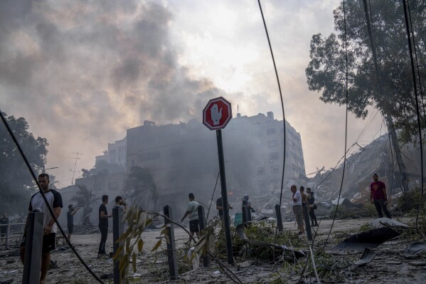 Palestinians inspect the rubble of a building after it was struck by an Israeli airstrike, in Gaza City, Sunday, Oct. 8, 2023. The militant Hamas rulers of the Gaza Strip carried out an unprecedented, multi-front attack on Israel at daybreak Saturday, firing thousands of rockets as dozens of Hamas fighters infiltrated the heavily fortified border in several locations by air, land, and sea, killing hundreds and taking captives. (AP Photo/Fatima Shbair)