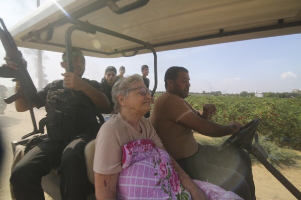 Palestinians transport a captured Israeli civilian, center, from Kibbutz Kfar Azza into the Gaza Strip on Saturday, Oct. 7, 2023. The militant Hamas rulers of the Gaza Strip carried out an unprecedented, multi-front attack on Israel at daybreak Saturday, firing thousands of rockets as dozens of Hamas fighters infiltrated the heavily fortified border in several locations by air, land, and sea and catching the country off-guard on a major holiday. (AP Photo/Hatem Ali)