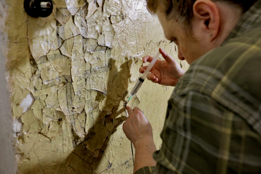 Stephanie Hoagland works to preserve a cross drawn into a wall