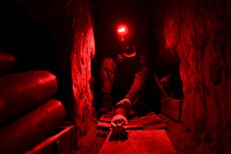 A member of service personnel checks a mortar shell inside a dugout at the frontline in Donetsk.