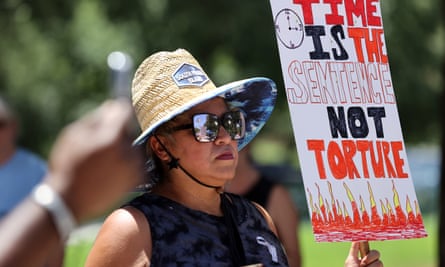 A woman holds up a sign during a demonstration against poor conditions caused by extreme heat in Texas jail cells 