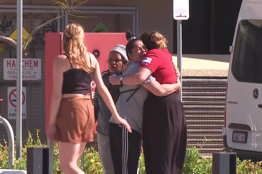 A group of people hug on a road