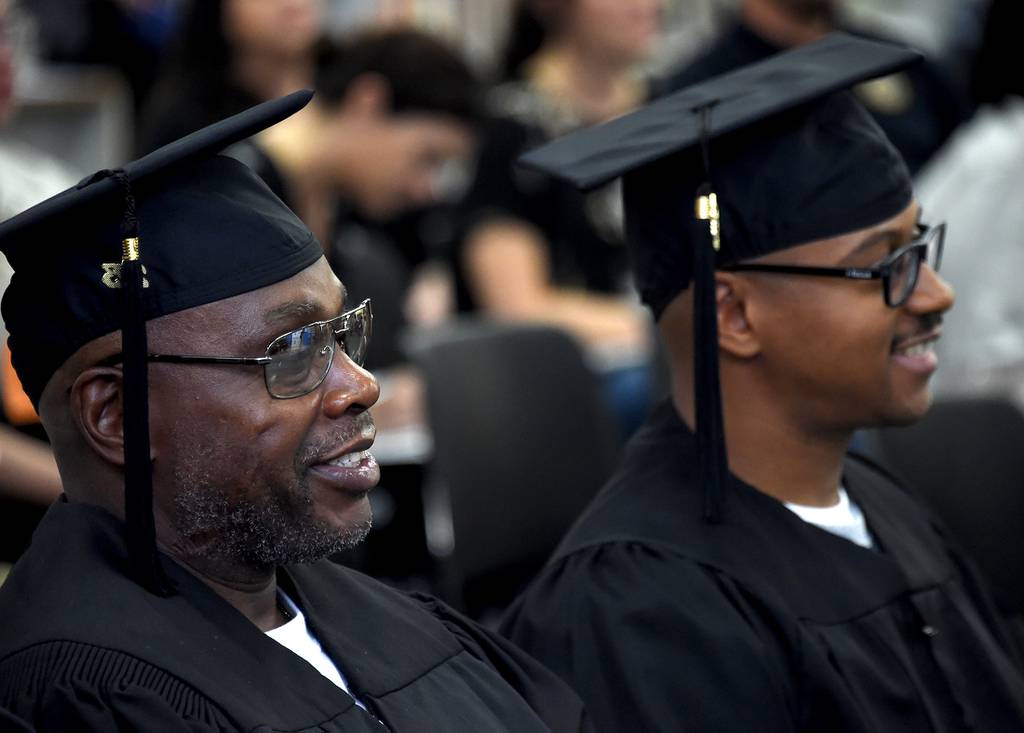 Michael White, left, and Bradford Bass, right, listen Oct. 6, 2023, during the inaugural commencement at Jessup Correctional Institution of the University of Baltimore’s Second Chance program.