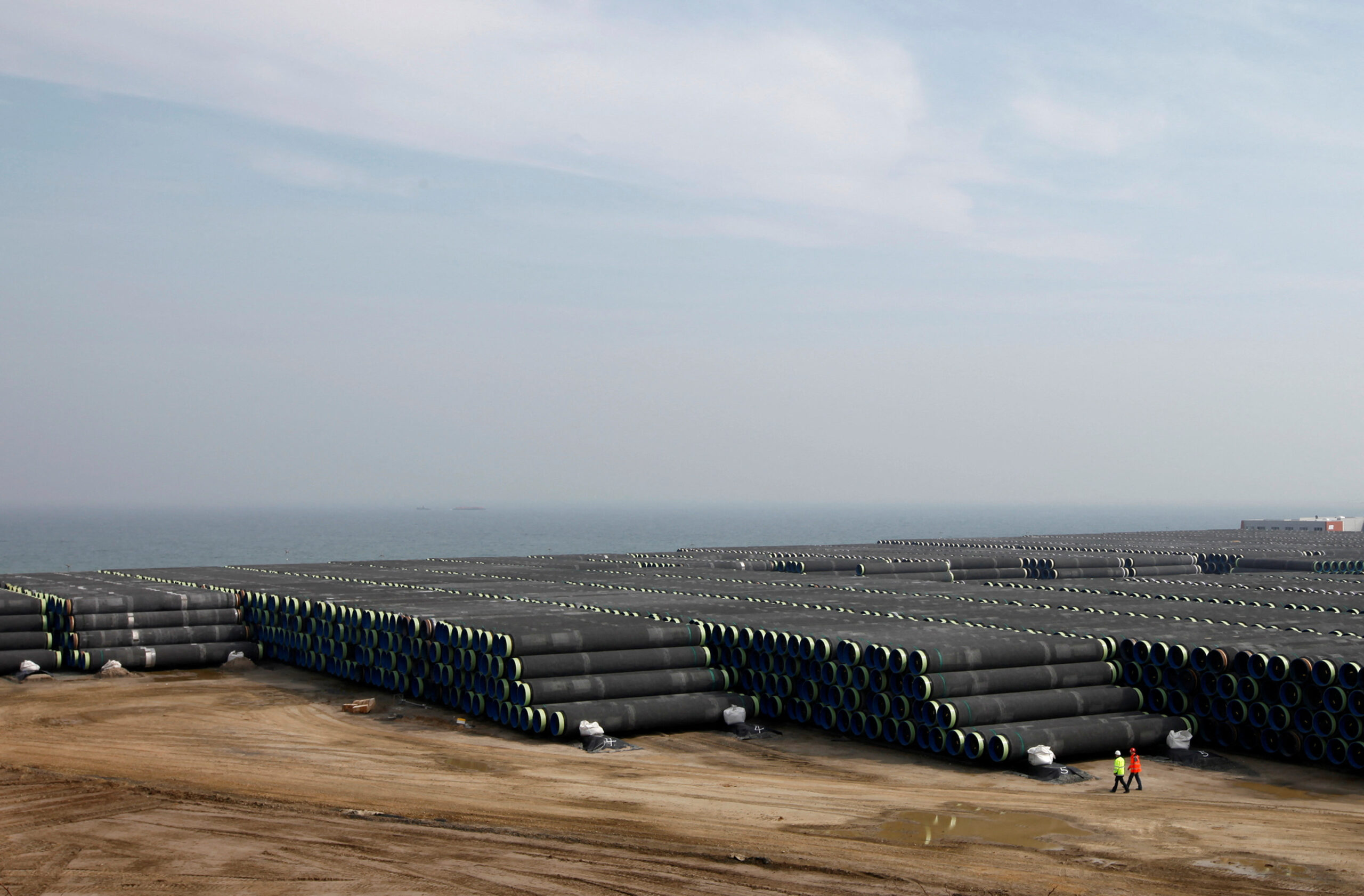 Technicians walk beside pipes for Nord Stream pipeline at storage in Mukran on the Baltic island of Ruegen