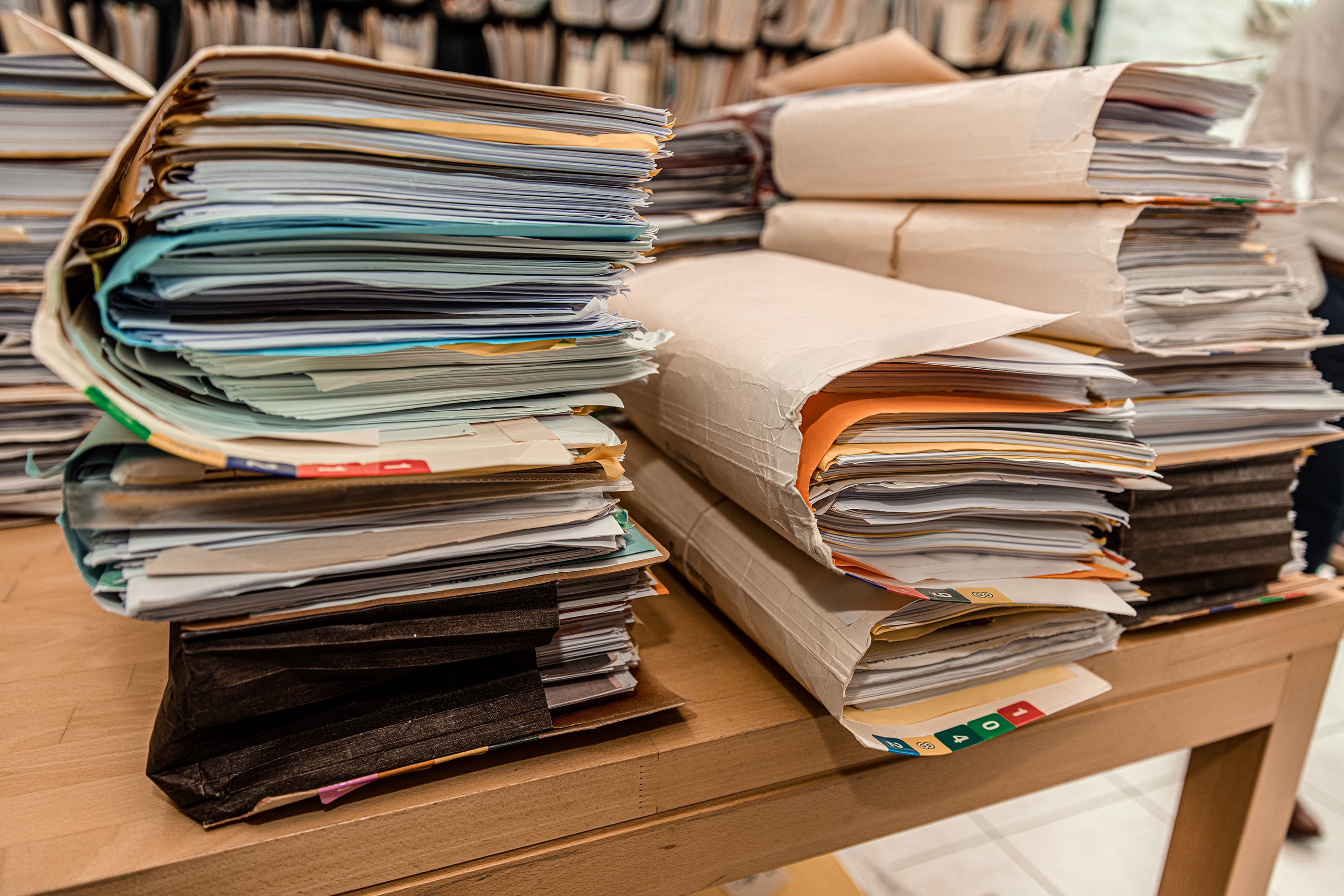 A photo of some stacks of file folders on top of a wooden desk.