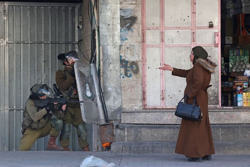 A woman gestures at Israeli security forces in the West Bank town of Hebron.