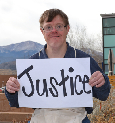 A man with a disability holds a sign up that says 