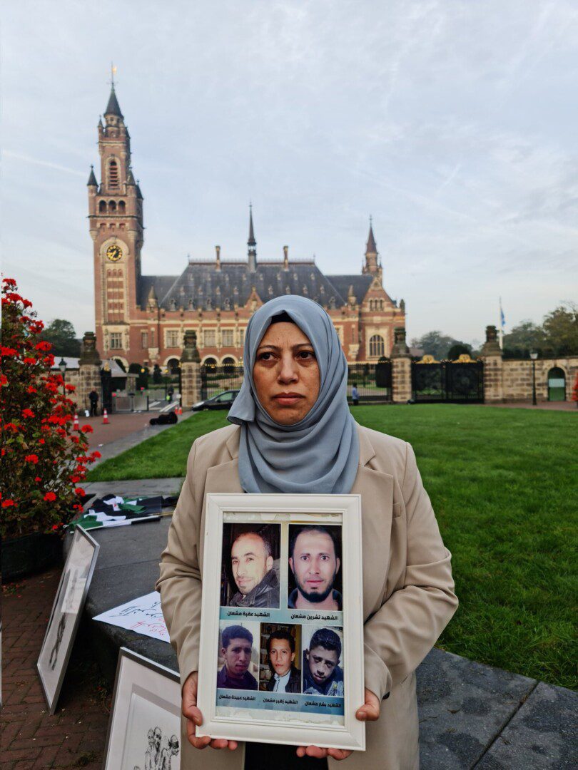 Yasmin Mashaan holds pictures of the five brothers she lost in Syria—four of whom were killed, forcibly disappeared or tortured by the regime—outside the Peace Palace in The Hague as hearings began in a landmark torture case brought against Syria by Canada and the Netherlands on Tuesday, 10/10/2023 (Caesar Families Association/Yasmin Mashaan)