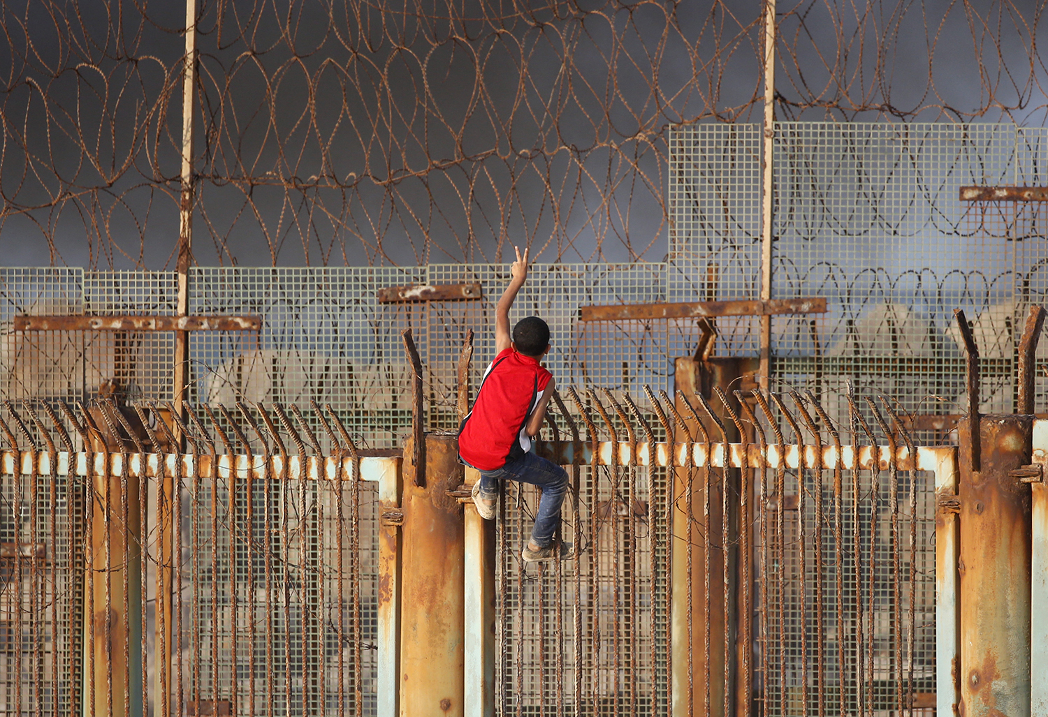 A young Palestinian protester climbs a fence during a demonstration on the beach near the maritime border with Israel in the northern Gaza Strip.