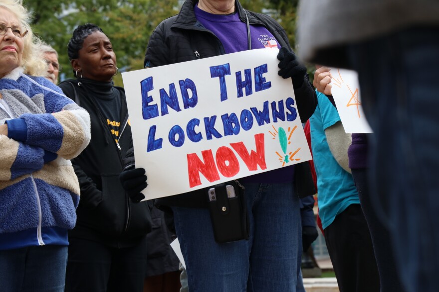 A sign reading “END THE LOCKDOWNS NOW!” is seen Oct. 10, 2023, during a protest at the Wisconsin State Capitol in Madison, Wis. WISDOM, a statewide faith-based social justice organization, organized the event. (Meryl Hubbard / Wisconsin Watch)