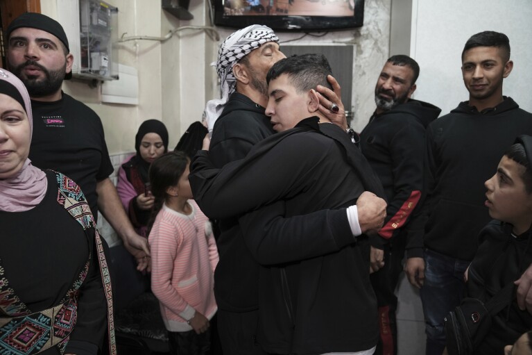 Ahmed Salaima, 14, center, a Palestinian prisoner released by Israel, is hugged by his father as he arrives home in the east Jerusalem neighborhood of Ras al-Amud Tuesday, Nov. 28, 2023. (AP Photo/Mahmoud Illean)