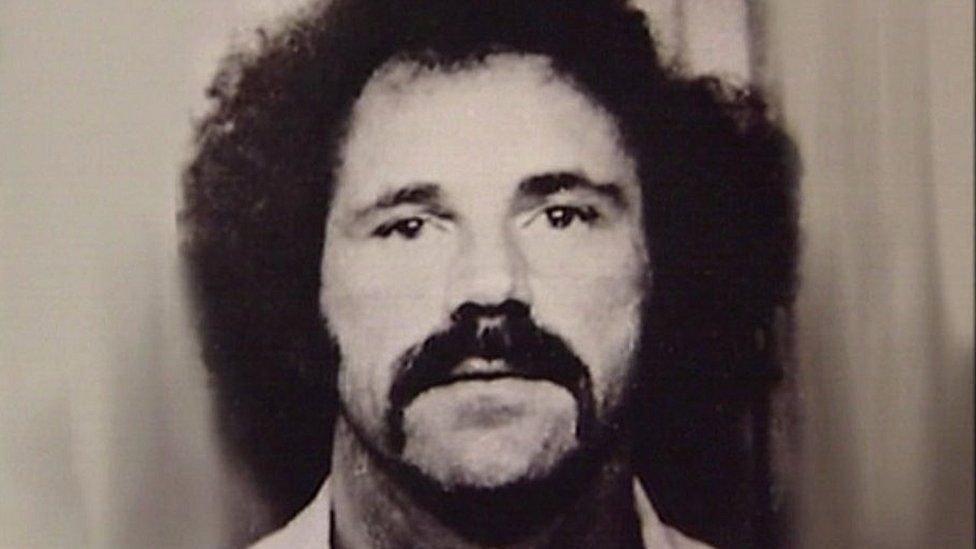 Ron Evans looking at the camera in a custody mugshot from the 1970s