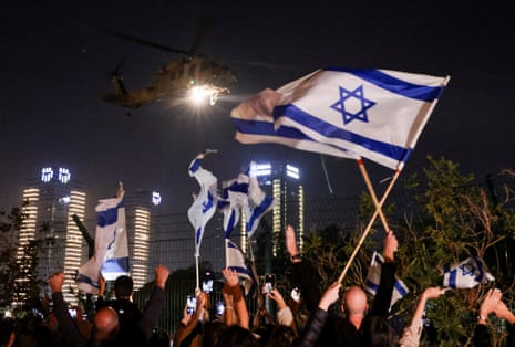 People wave Israeli flags as helicopter carrying hostages released as part of a deal between Israel and Hamas arrives at Schneider Children's Medical Center in Petah Tikva, Israel.