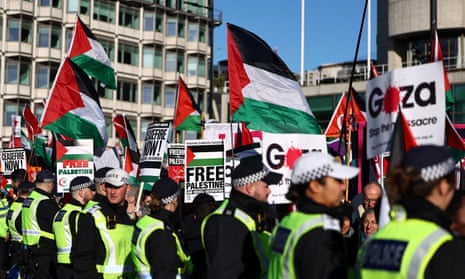 A line of Metropolitan police officers next to protesters taking part in a pro-Palestine march