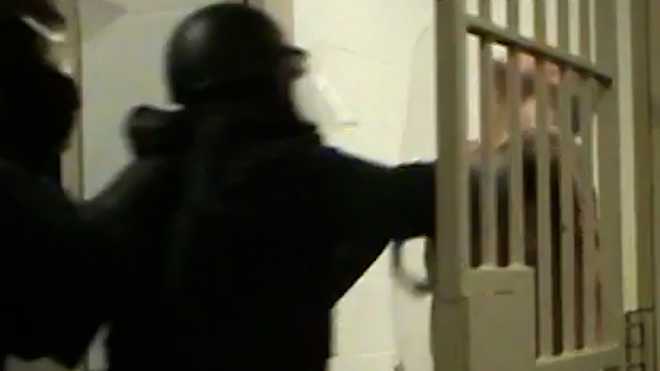 officer seth bourget, holding the plexiglass shield, moments before slamming the shield into inmate kerry tropasso's chin during a forced cell entry.