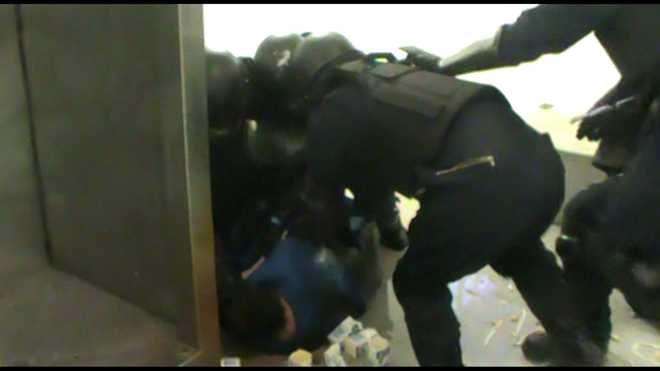 officer seth bourget, holding the plexiglass shield, moments before slamming the shield into inmate kerry tropasso's chin during a forced cell entry.