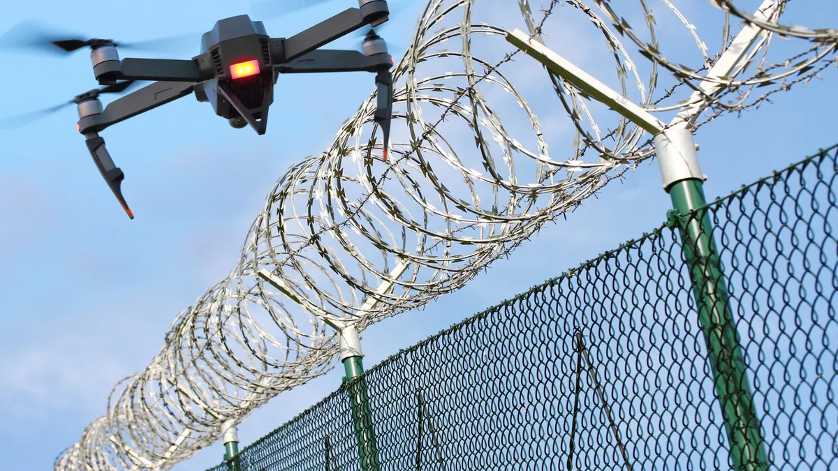 Representational image of drone near barbed prison fence.