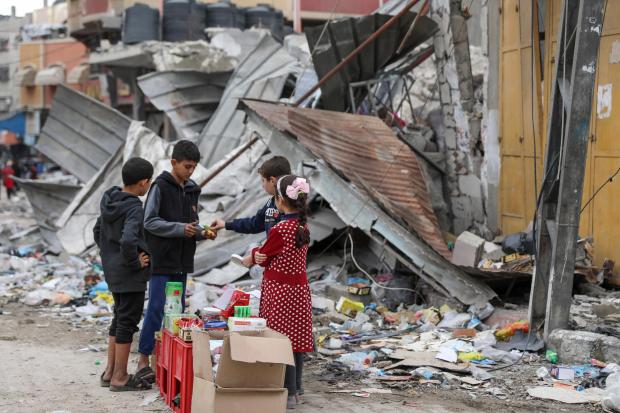 Palestinian children sell sweets in front of the rubble of a destroyed building in Jebaliya refugee camp, Gaza Strip, Tuesday, Nov. 28, 2023, on the fifth day of the temporary ceasefire between Hamas and Israel. (AP Photo/Mohammed Hajjar)