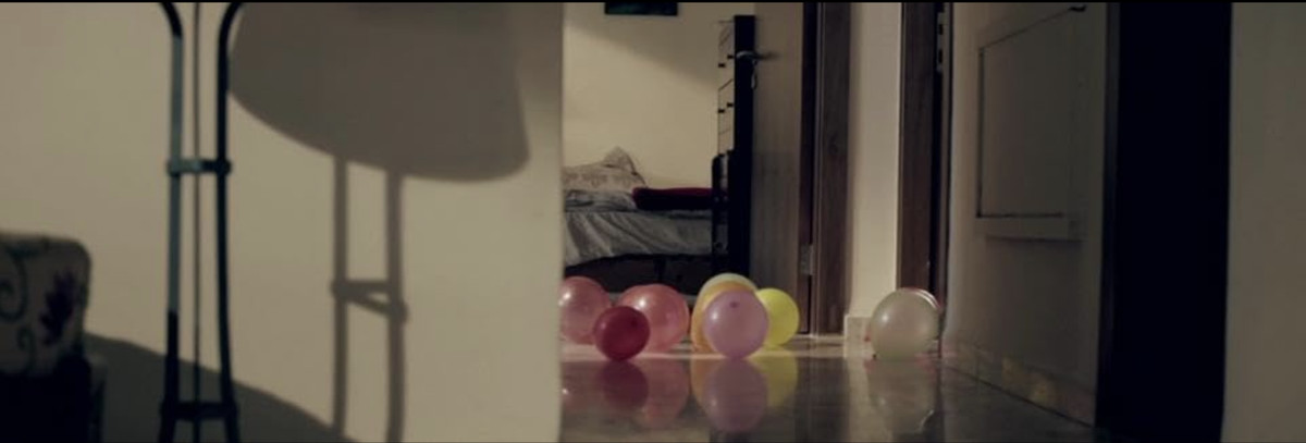 An apartment hallway with balloons all over the ground.