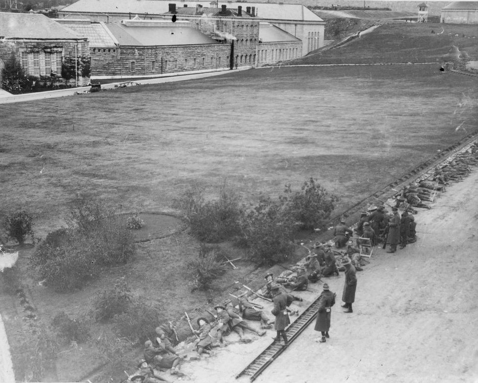 Soldiers surround a prison, guns trained on the buildings.