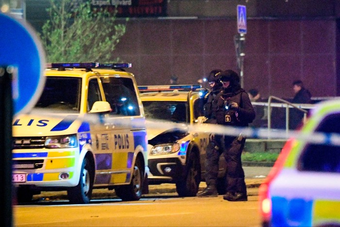 Police officers inspect parked police cars