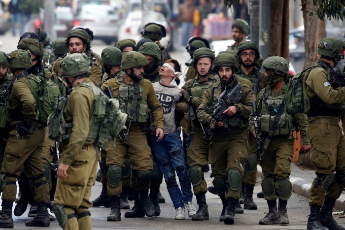 Israeli soldiers detaining a young Palestinian following clashes after a protest in Hebron, West Bank in December 2017